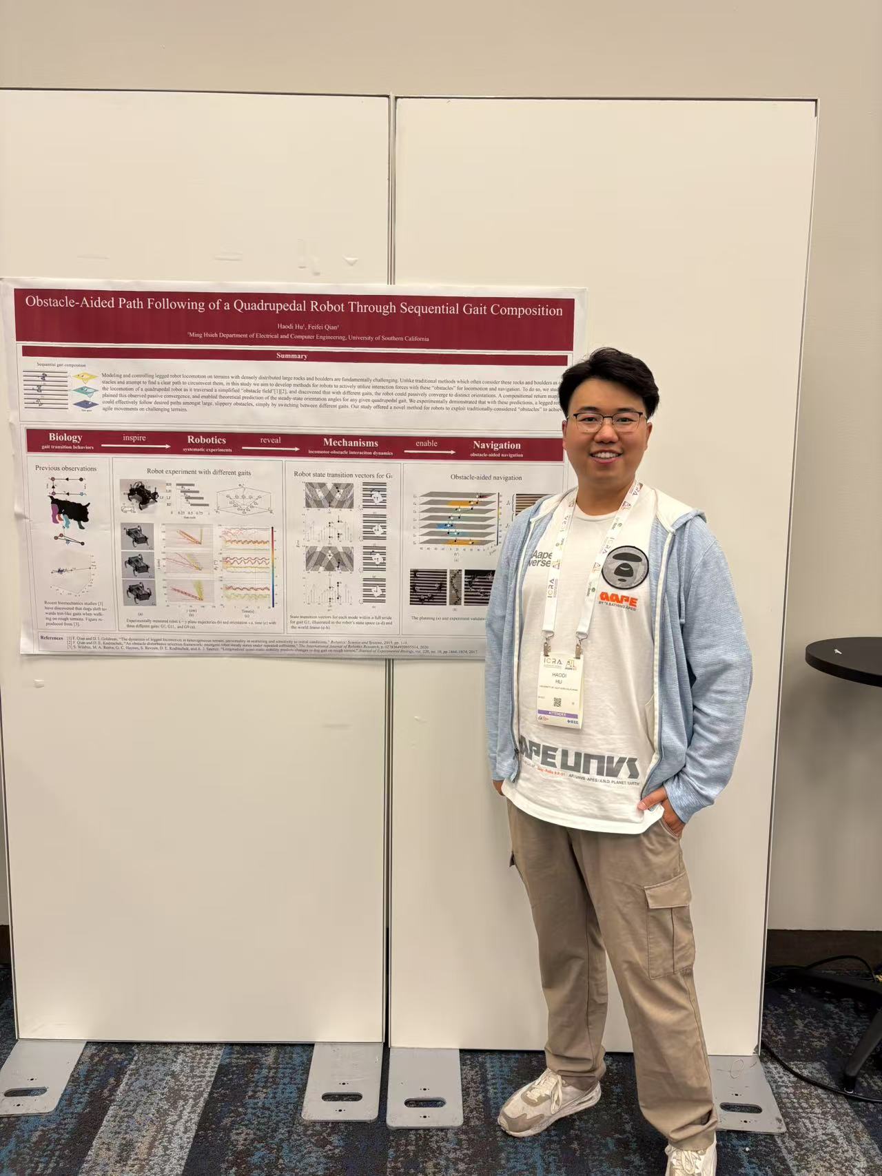 Haodi Hu standing beside an earlier robotics poster presentation.